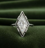 Kite-shaped diamond ring on dark olive green velvet