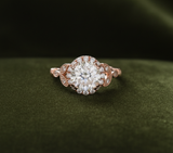Rose gold halo ring straight-on view on dark olive green velvet