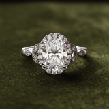 White gold oval halo engagement ring on dark olive green velvet
